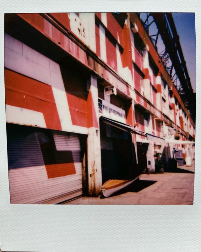 A square, polaroid photograph of the red and white "River Project" building at Hudson River Park.